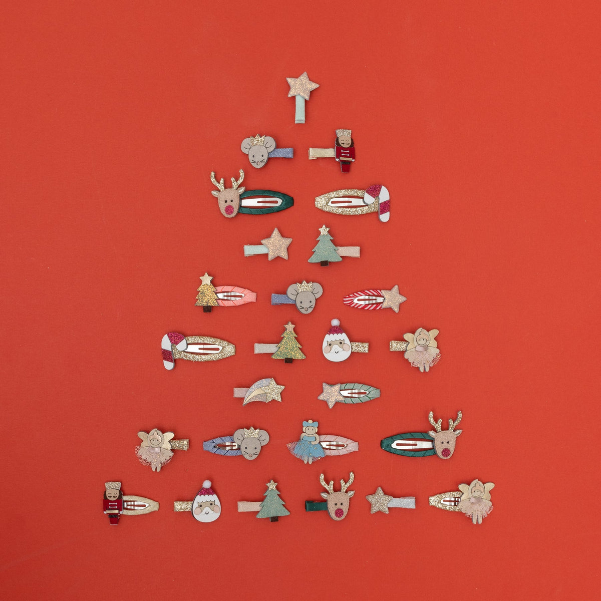 Collection of decorative hair clips arranged in a Christmas tree shape on a red background