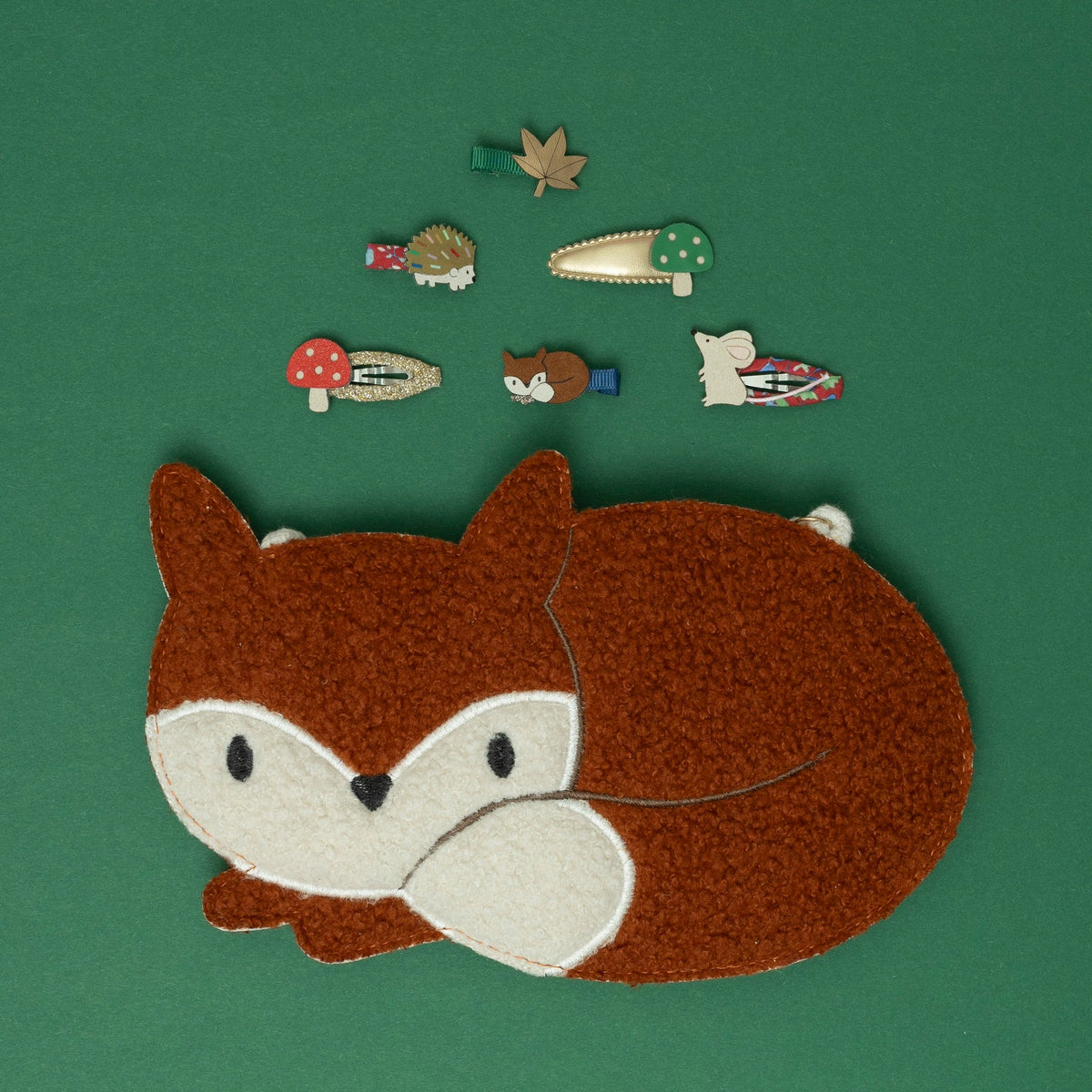 Embroidered patch of a fox on a green background with small embroidered animals and objects.
