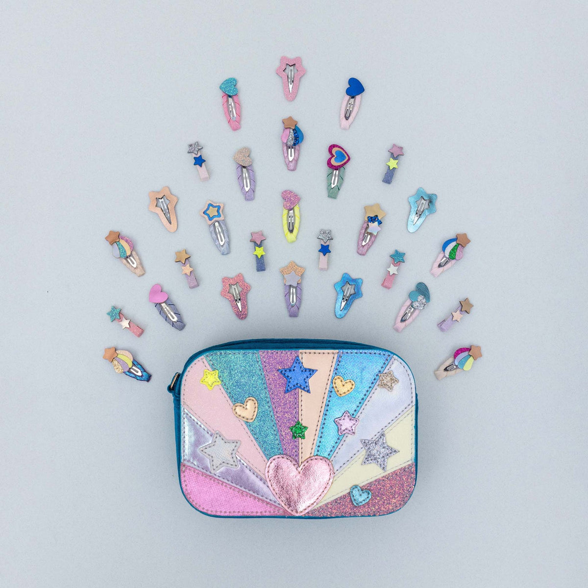 A pastel multicolor zippered pouch with a heart and star applique design, surrounded by a fan arrangement of matching star-shaped hair clips on a light gray background.