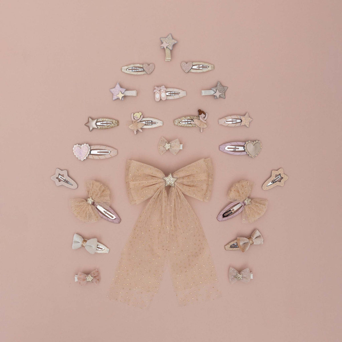 A collection of pastel pink and beige hair clips, bows, and barrettes arranged in a tree-like structure with a large glittery bow at the center, set against a solid dusty pink background.
