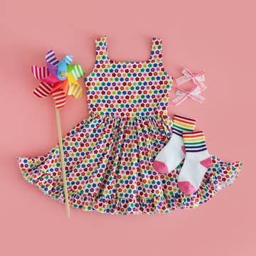 Colorful polka dot dress with matching socks and a windmill on a pink background