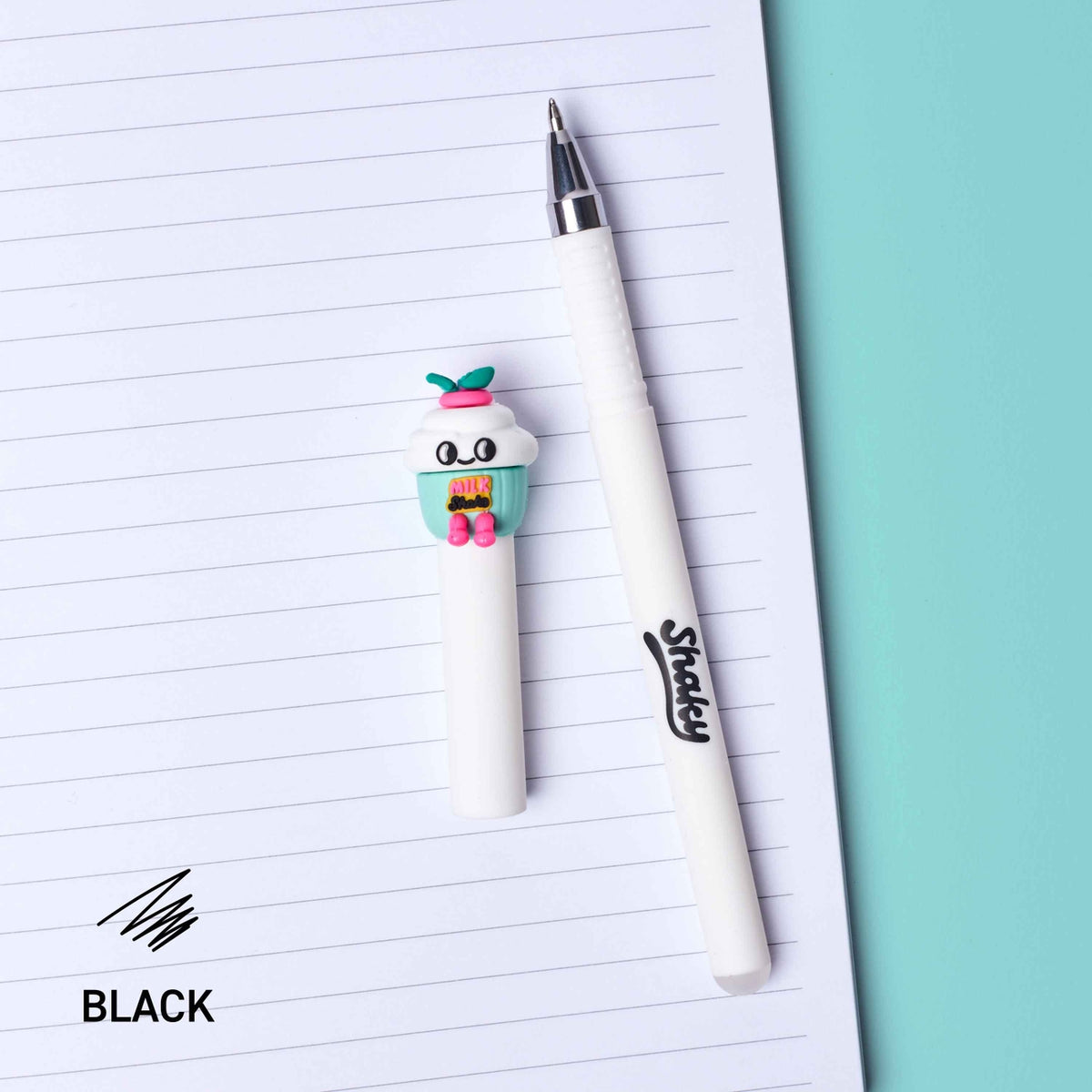 A white gel pen with a cute cupcake character on the cap, placed next to an open lined notebook on a teal background. The brand name 'Sprey' is printed on the pen barrel, and the text 'BLACK' appears in the bottom left corner.