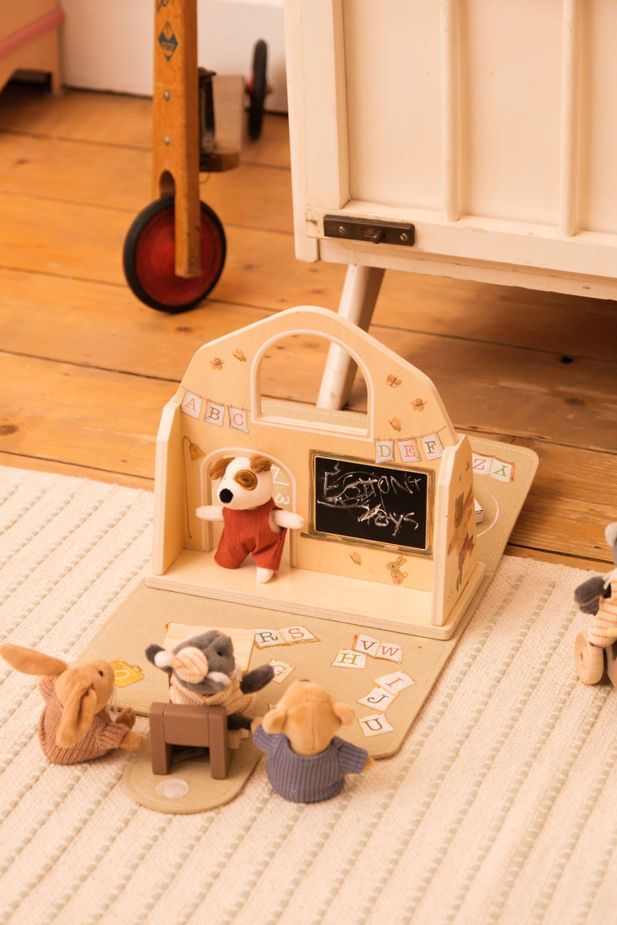 Wooden toy set with animal figures and a chalkboard on a wooden floor.