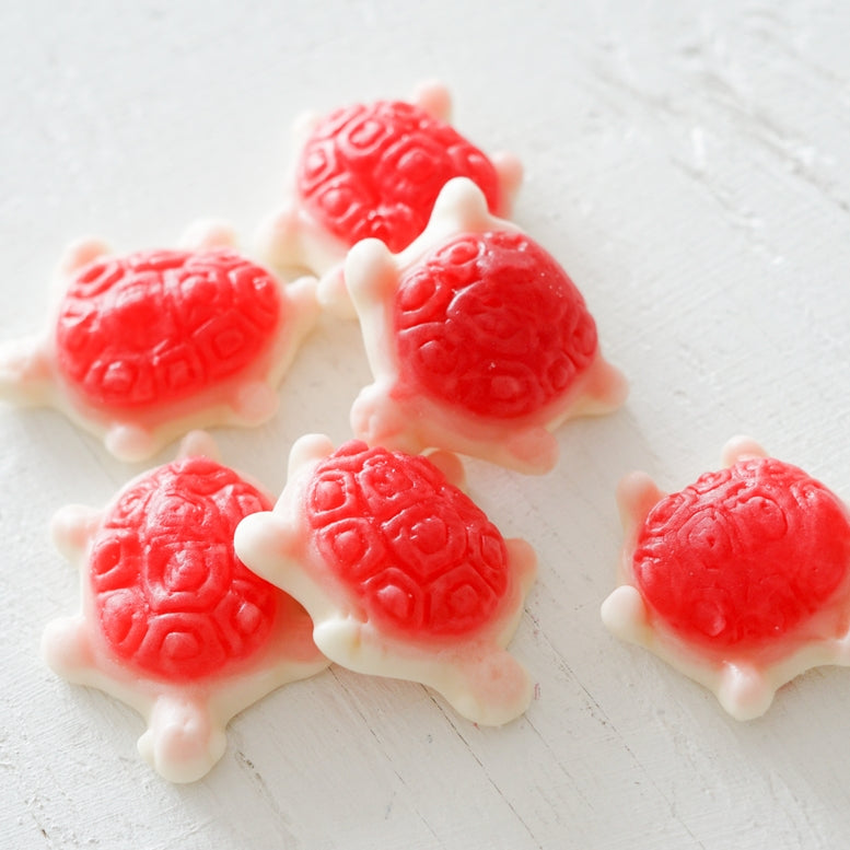 Red and white turtle-shaped candies on a light wooden surface