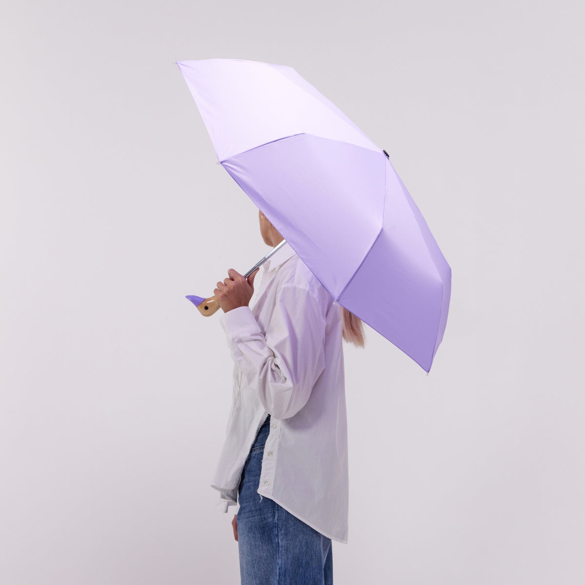Person holding a large purple umbrella against a plain background