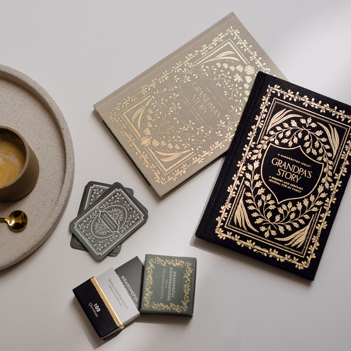 Decorative books with ornate covers, a cup of coffee, and glasses on a light surface.