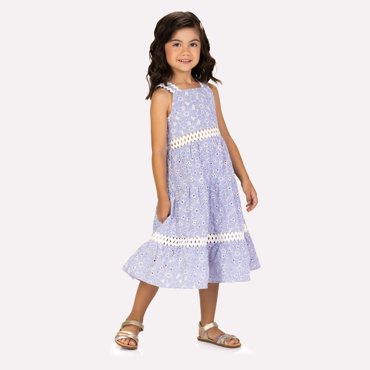 Young girl wearing a light blue floral dress with white trim on a white background
