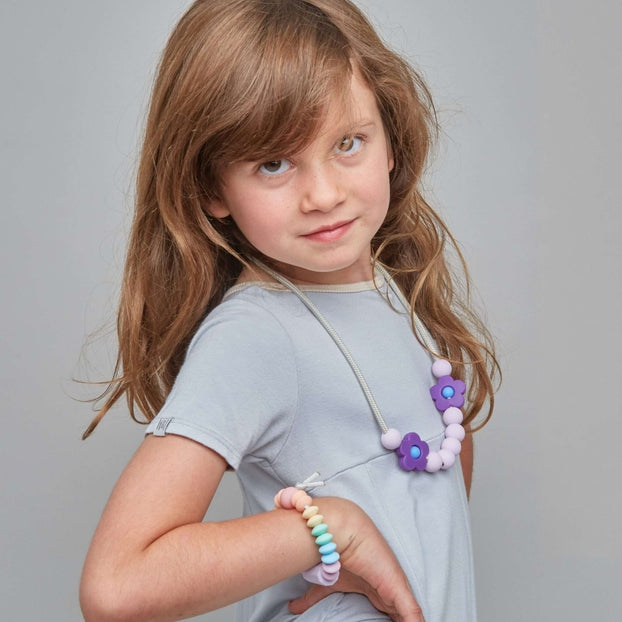 Young girl in a gray dress with jewelry on a gray background