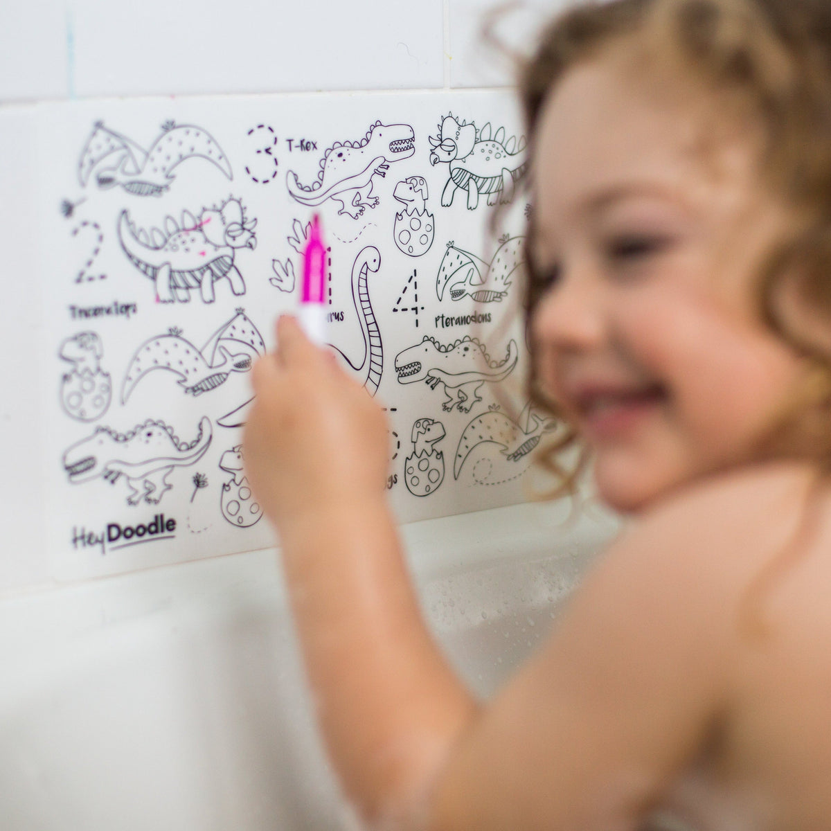 Child coloring a dinosaur-themed coloring book with a pink marker.