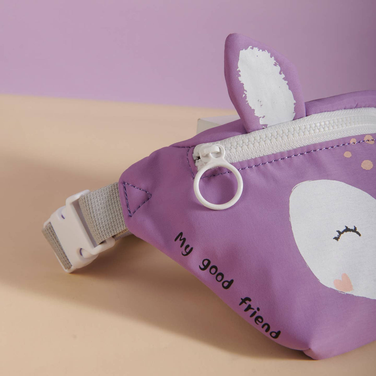 Purple pouch with cartoon design and 'My good friend' text on a beige surface.