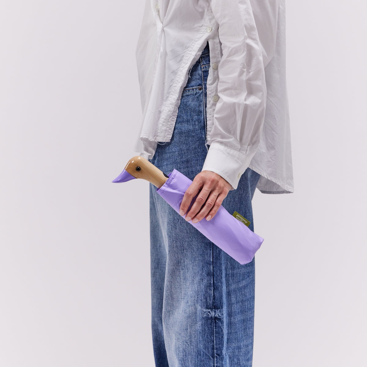 Person holding a purple bag with a duck-shaped handle against a plain background