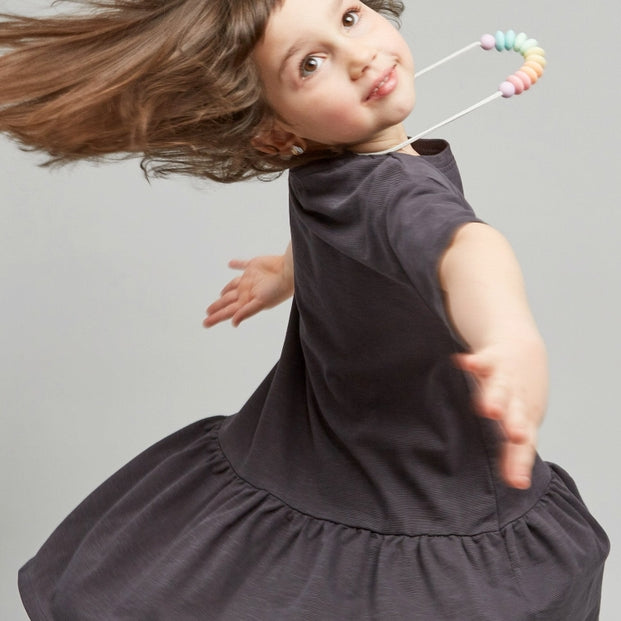 A young girls wearing gray dresses standing against a plain background