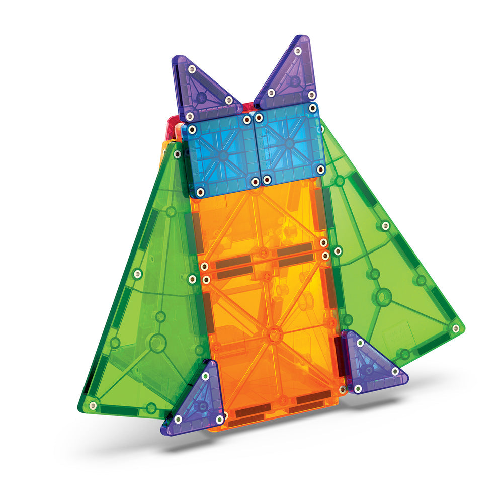 A geometric, rocket-shaped structure built with colorful translucent magnetic tiles from the microMAGS 20 Piece Combo Set by Magna-Tiles, featuring a central orange panel, large green triangular wings, and purple rectangular and triangular accents at the top and base.