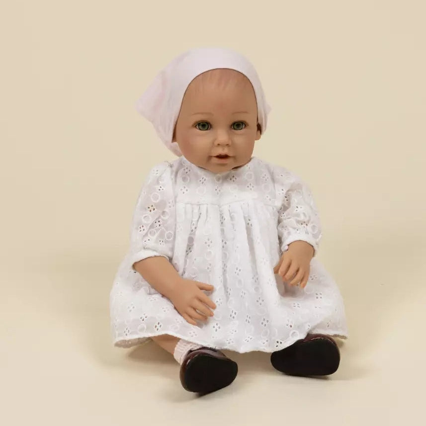 Doll wearing a white lace dress and headscarf on a beige background