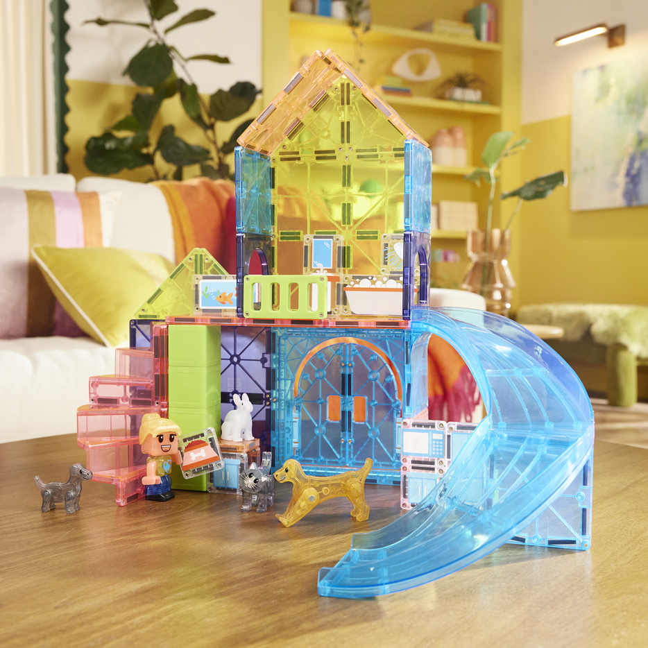 Colorful toy house with accessories on a wooden floor in a living room.
