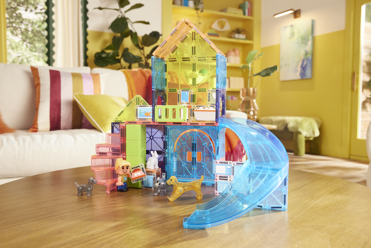 Colorful toy house with accessories on a wooden floor in a living room.