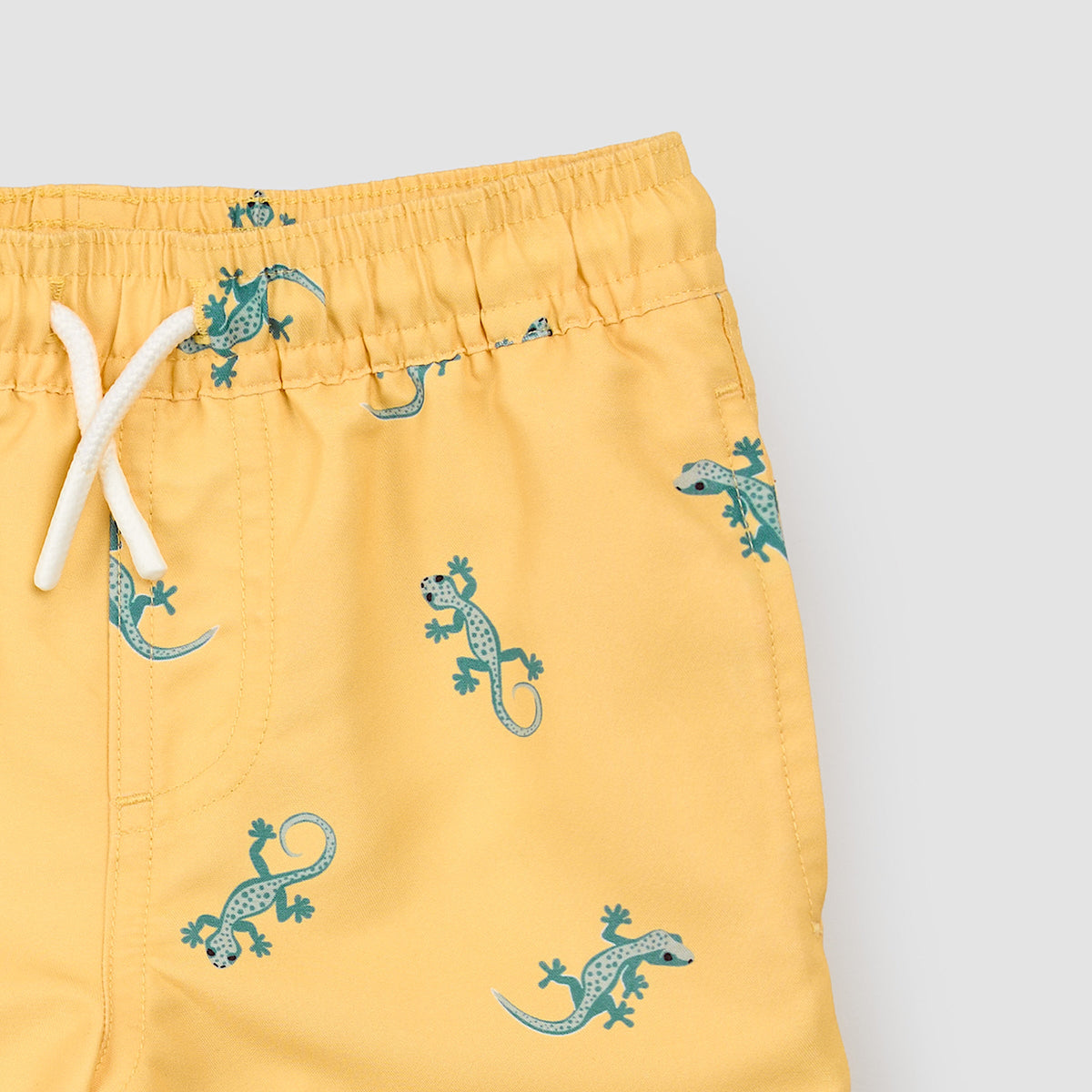 Yellow shorts with green lizard pattern on a light gray background