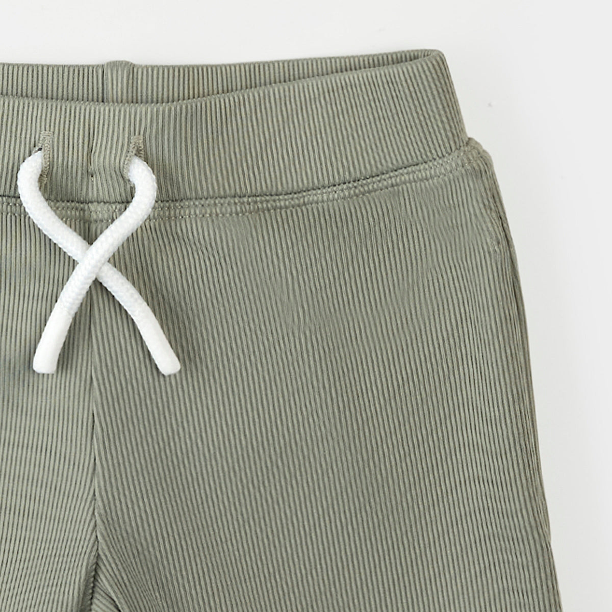 Green ribbed pants with white drawstring on a light gray background