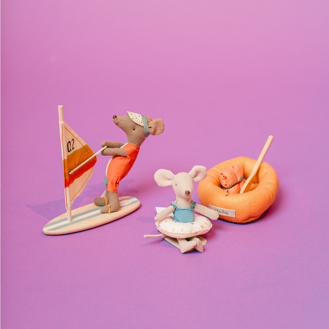 Toy mice with beach accessories on a purple background