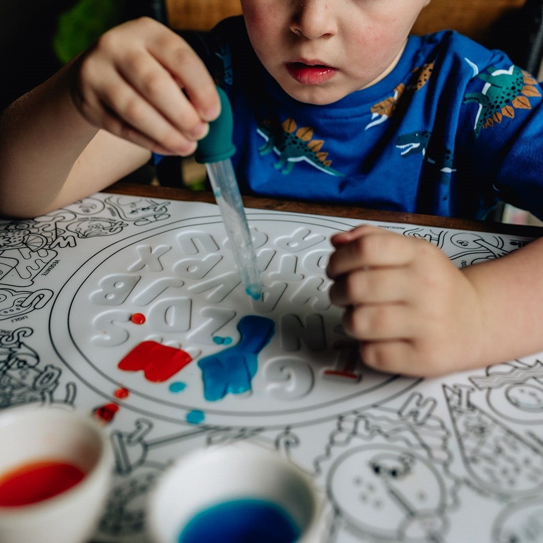 Child painting on a coloring book with blue paint