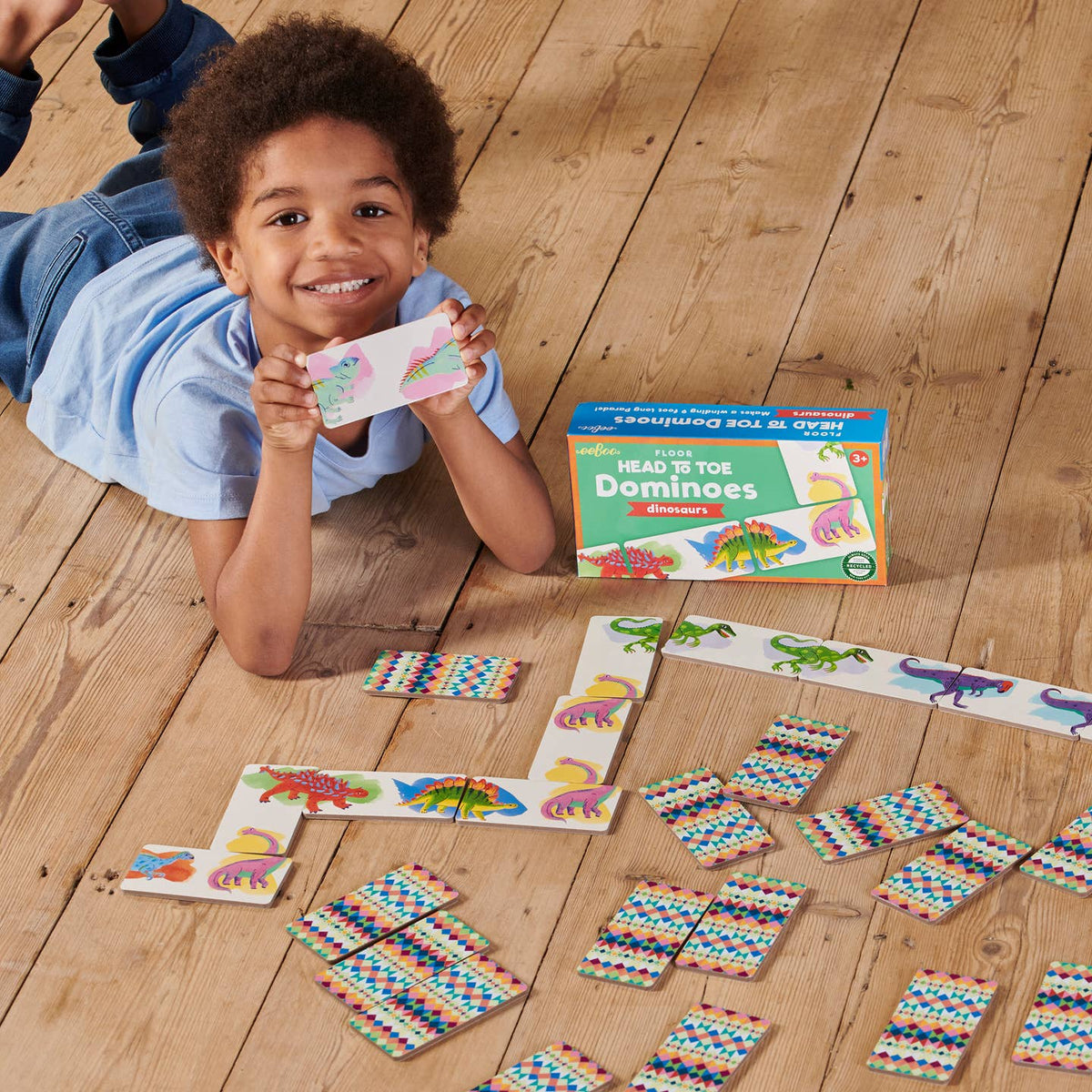 Child playing with colorful dominoes on a wooden floor