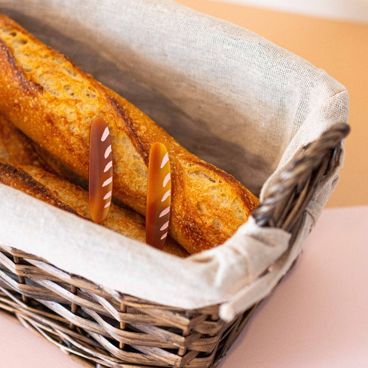 Baguette in a wicker basket with decorative straws on a light background