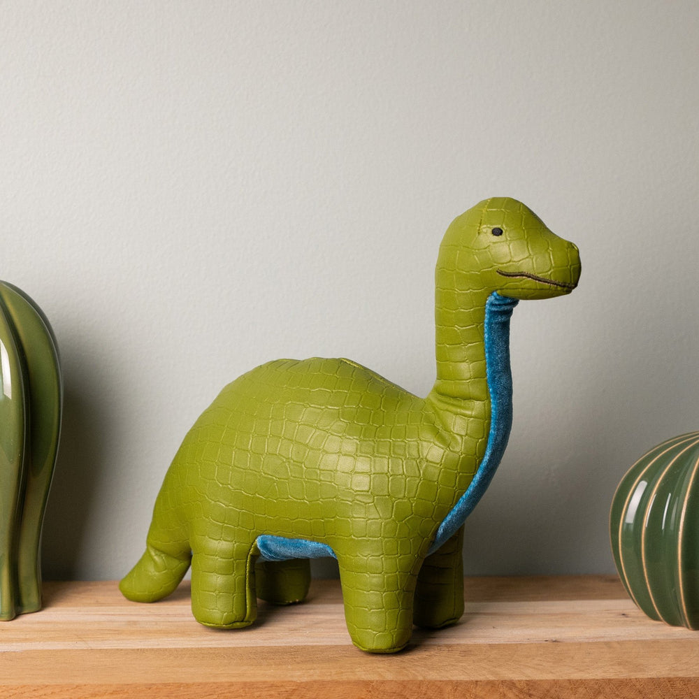 Green dinosaur-shaped object on a wooden surface with a neutral background