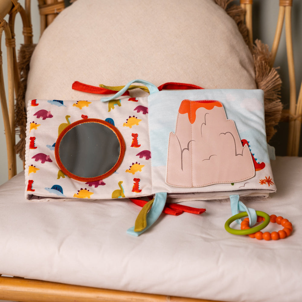 Children's soft book with colorful illustrations and toys on a cushioned surface