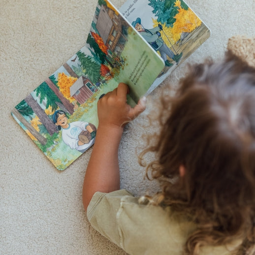 A children's board book cover titled When Fall Comes by Amée Bissonette, illustrated by Erin Hourigan. The illustration depicts a family walking with a dog across stepping stones in a shallow stream surrounded by autumn trees and a small waterfall, with a deer visible in the background.