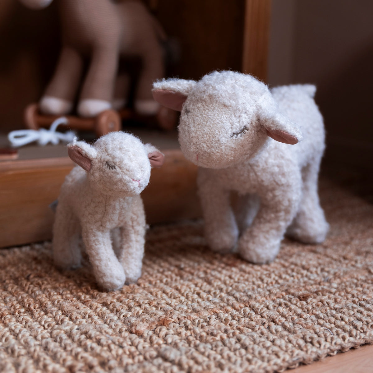 Two fluffy toy sheep on a textured surface with blurred background