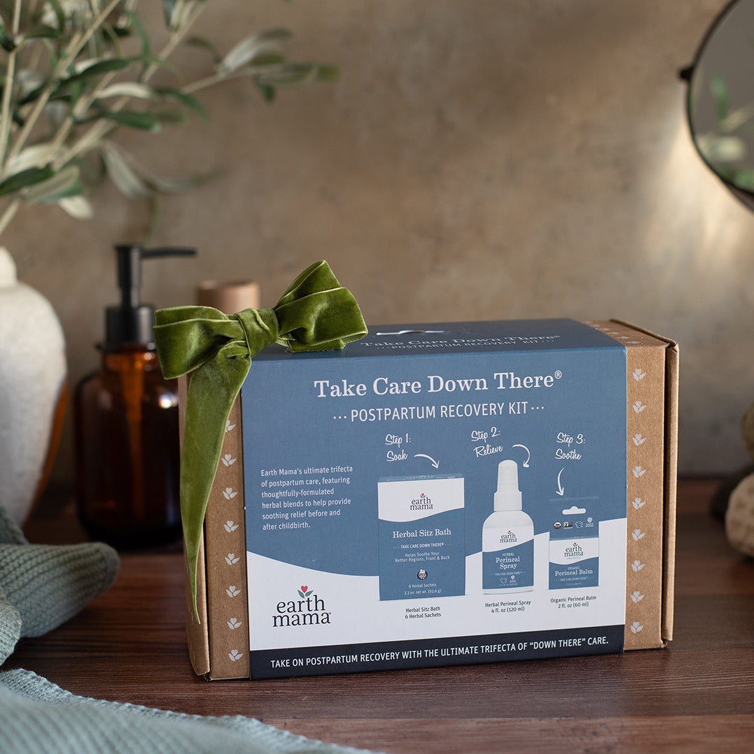 Earth Mama postpartum recovery kit with a green ribbon on a wooden surface.