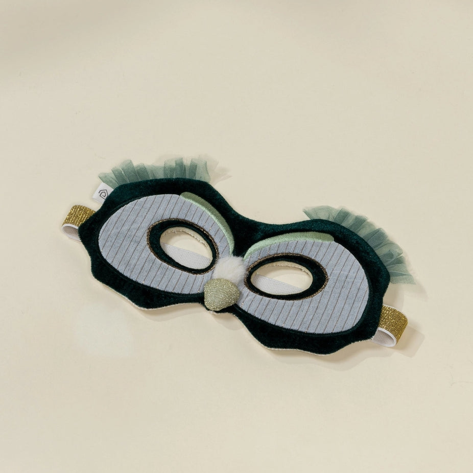 Eye mask with black frame and green fringes on a beige background