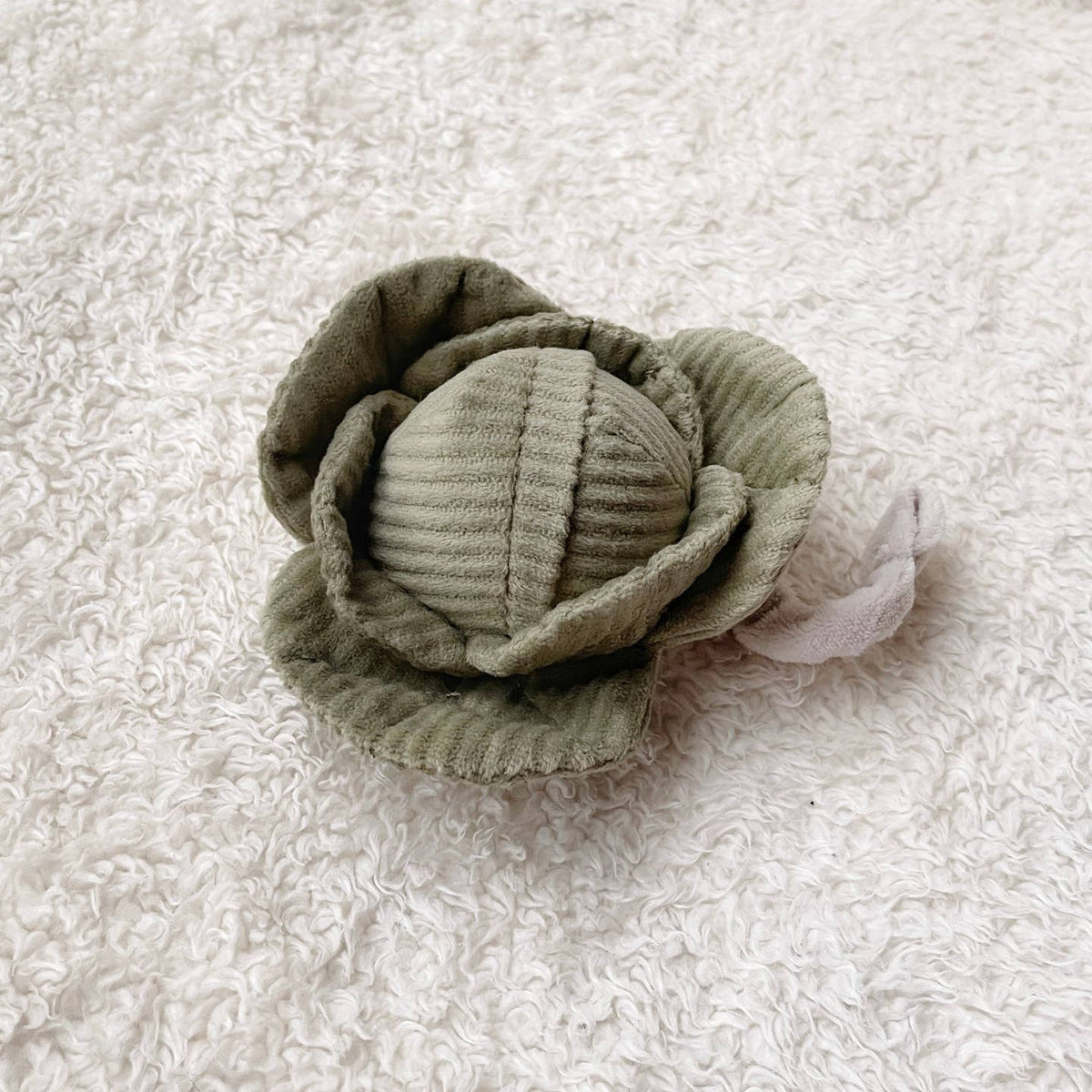 Green fabric flower on a textured white background