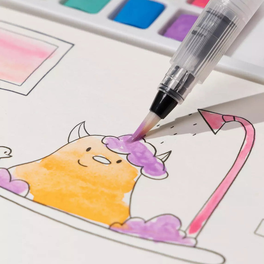 A close-up of a watercolor brush pen being used to color a cartoon character in a bathtub, with a watercolor palette visible in the background.