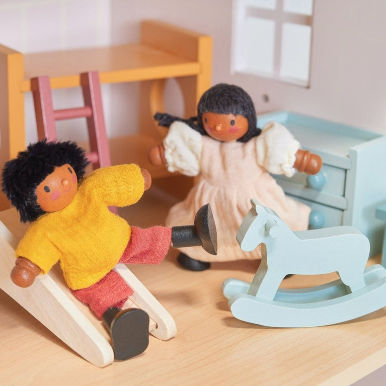 Two wooden doll figures playing in a miniature room setting with a wooden bunk bed, a slide, a light blue rocking horse, a chest of drawers, and a bedside table.