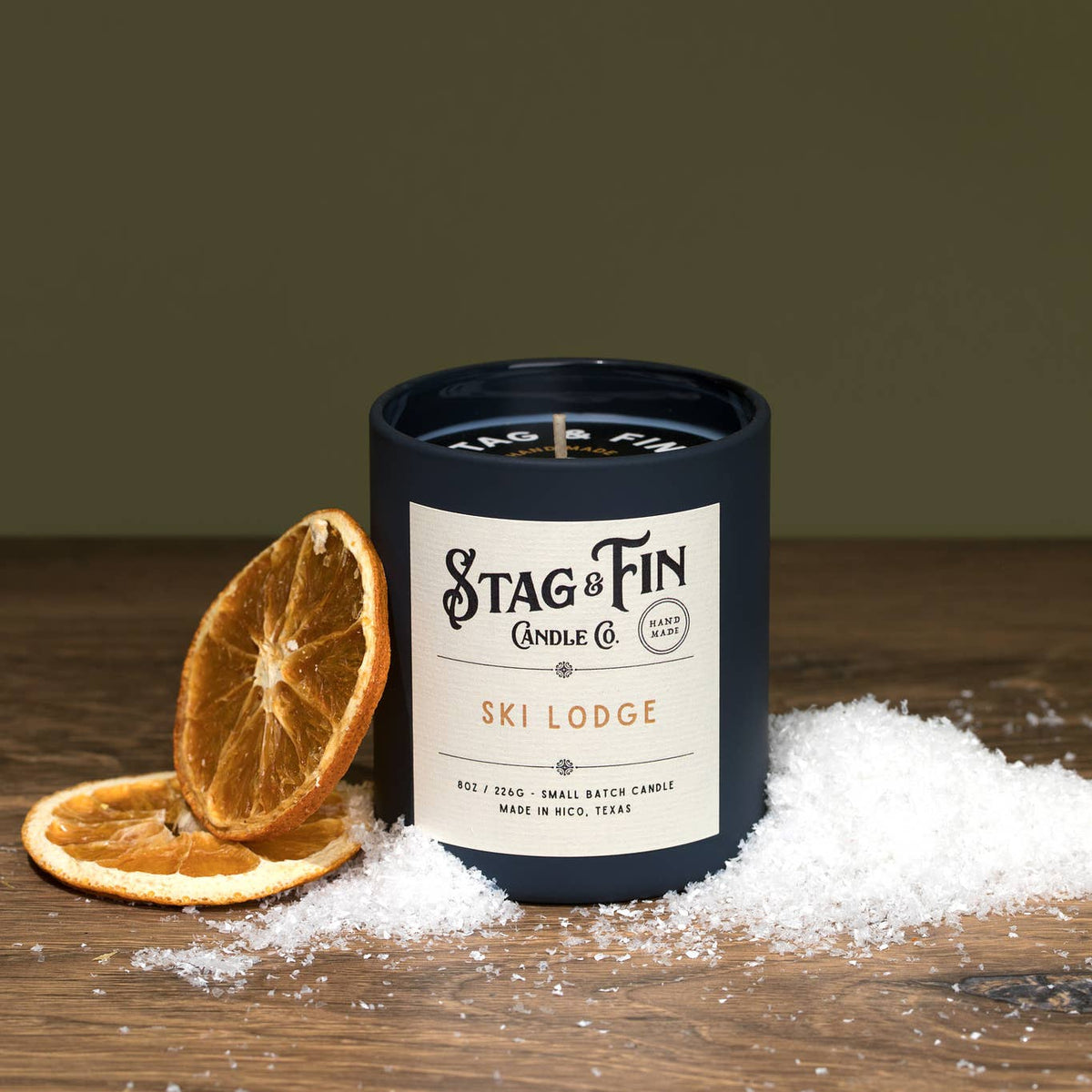 Stag & Fin candle with dried oranges and snow on a wooden surface