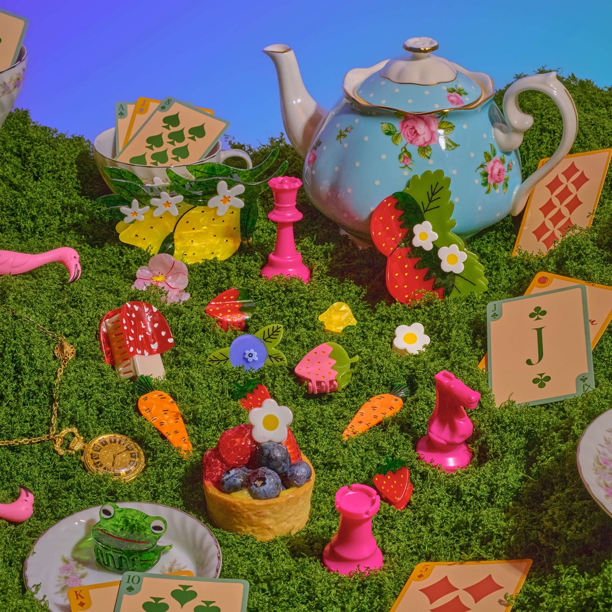 Colorful tea party scene with a teapot, cards, and toys on a grassy background