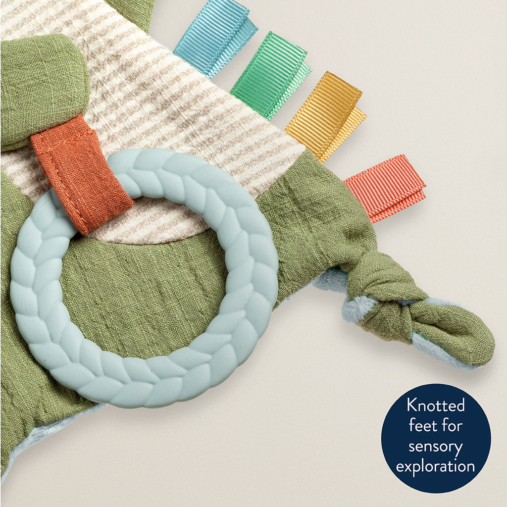 Colorful baby toy with knotted feet on a textured surface