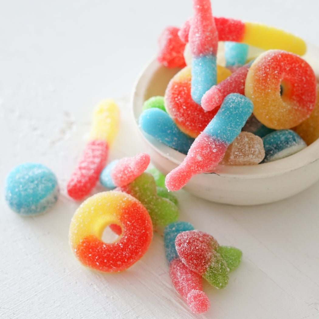 Colorful gummy candies in a white bowl on a light background