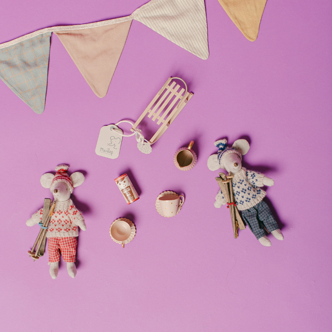 Two small mouse figurines with accessories on a purple background with bunting.