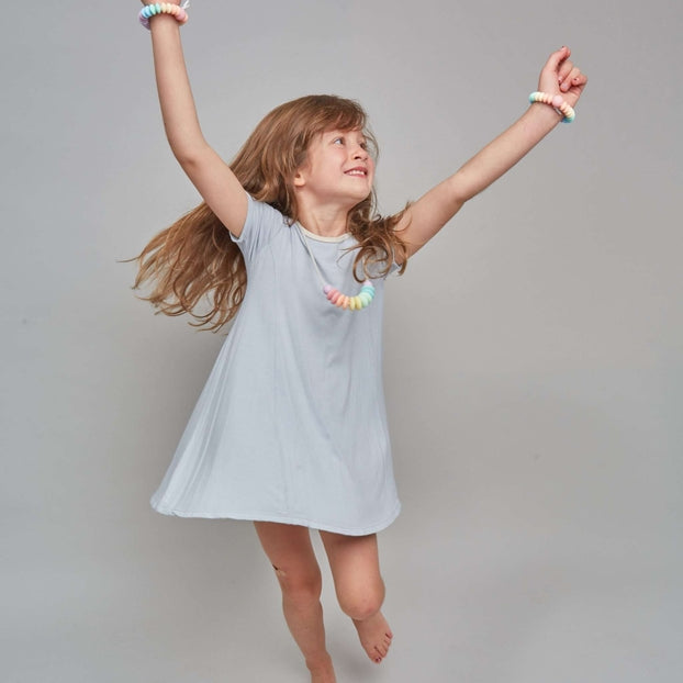 Young girl in a light blue dress posing against a plain background