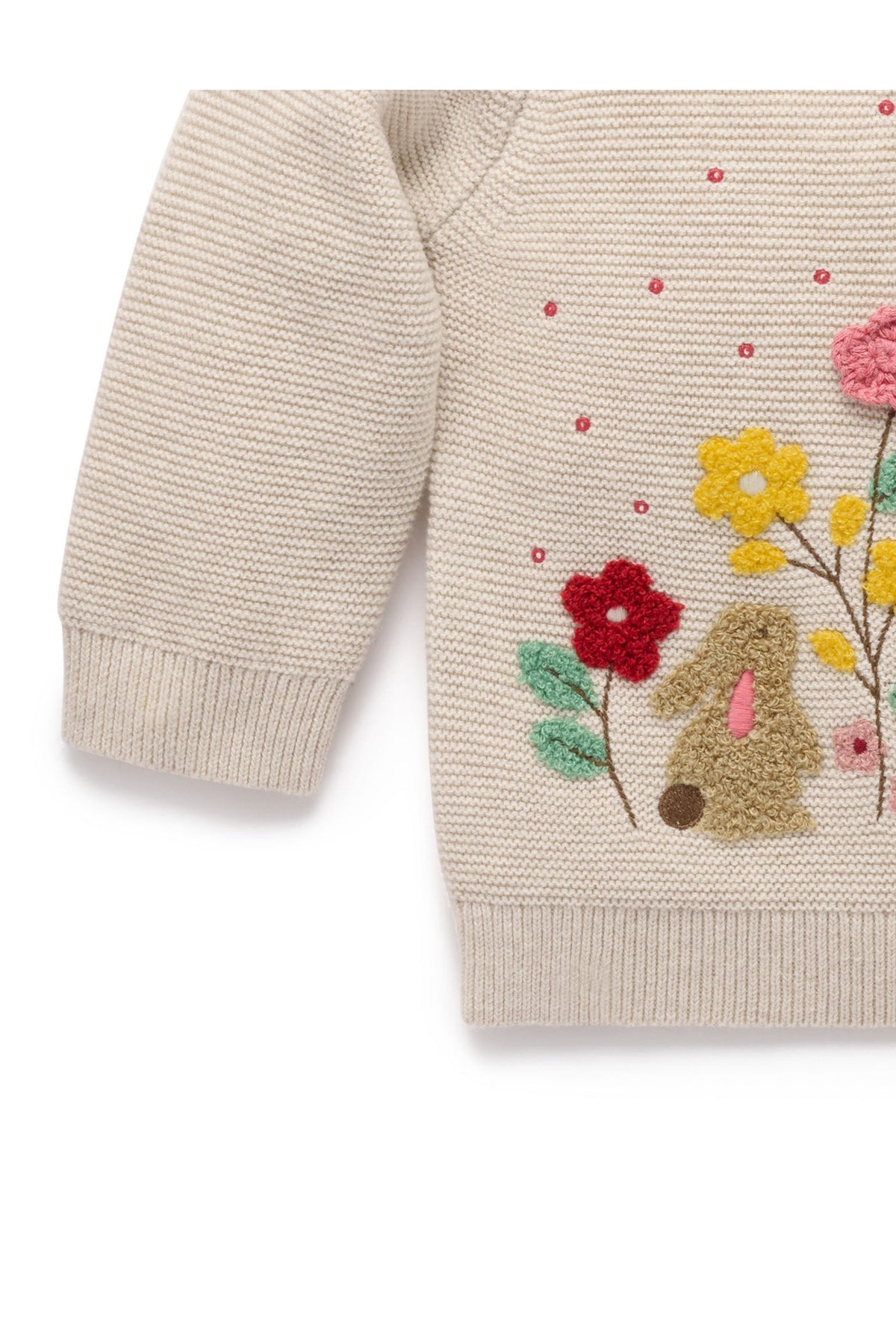 Close-up of a cream-colored knit sweater featuring a colorful embroidered bunny and wildflower design on the front.