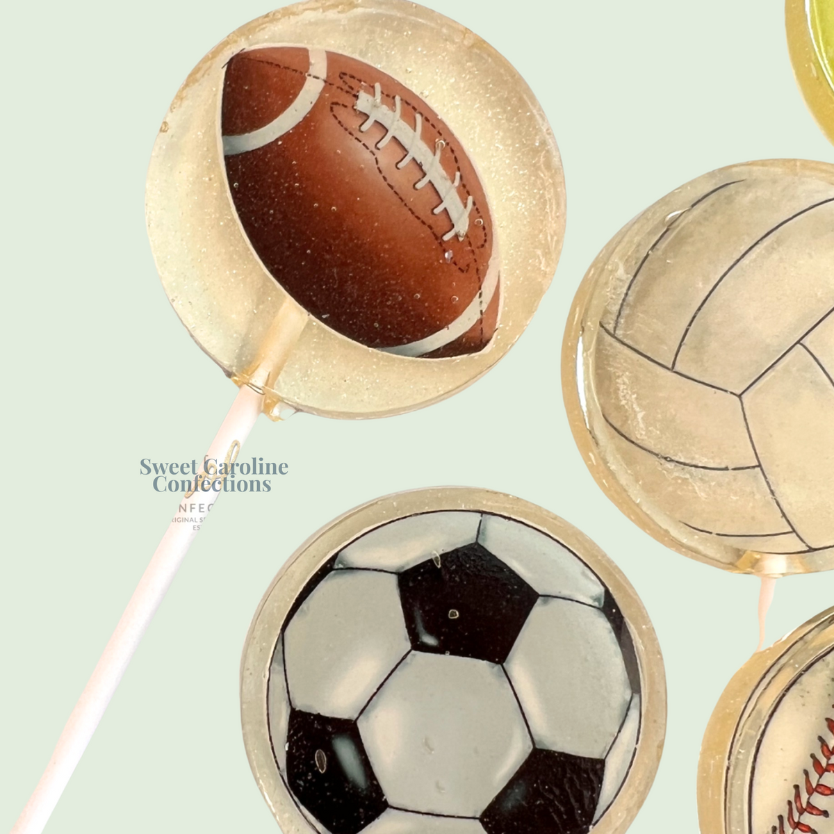 Sweets shaped like sports balls on sticks with 'Sweet Caroline Confections' branding.