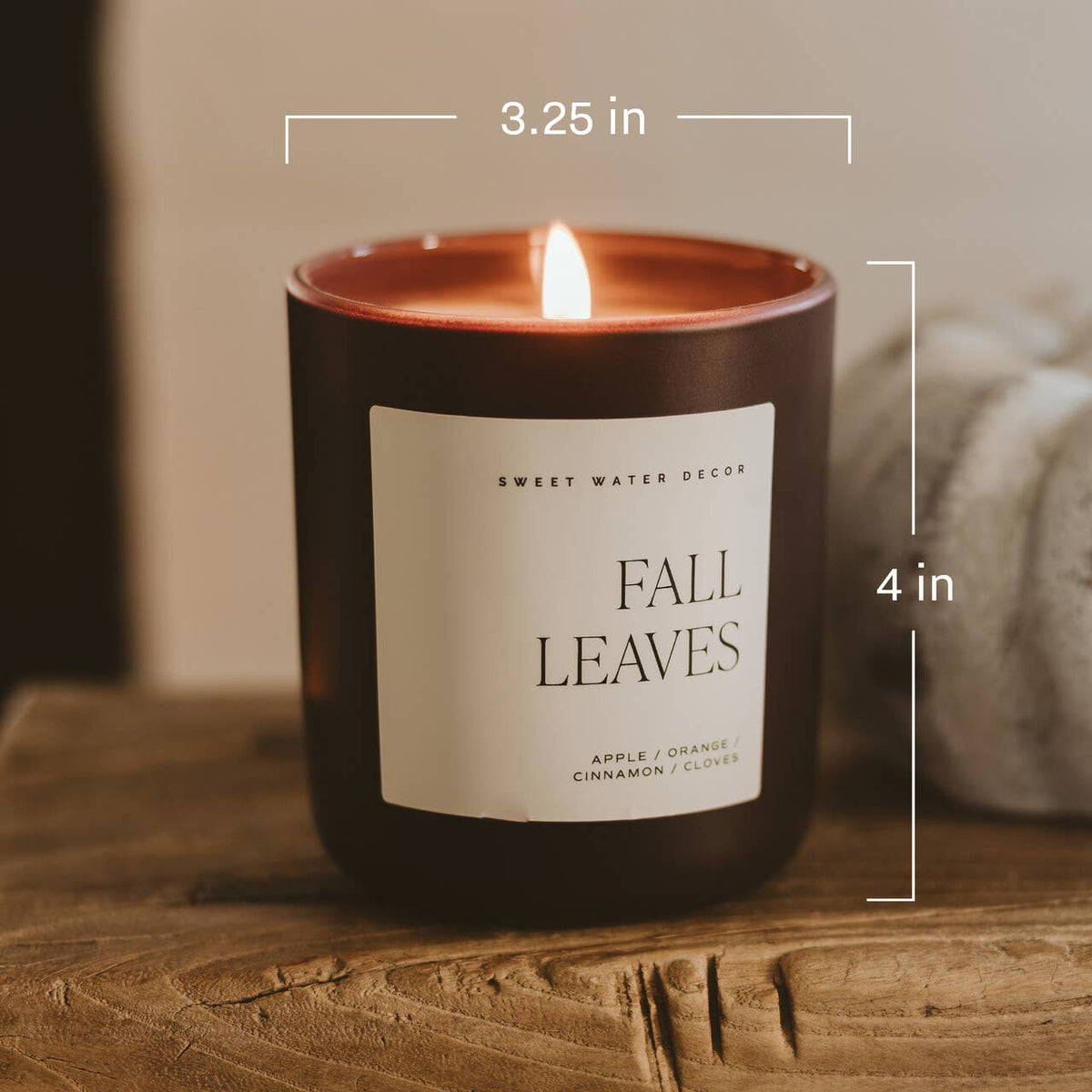 Candle labeled 'Fall Leaves' with dimensions on a wooden surface