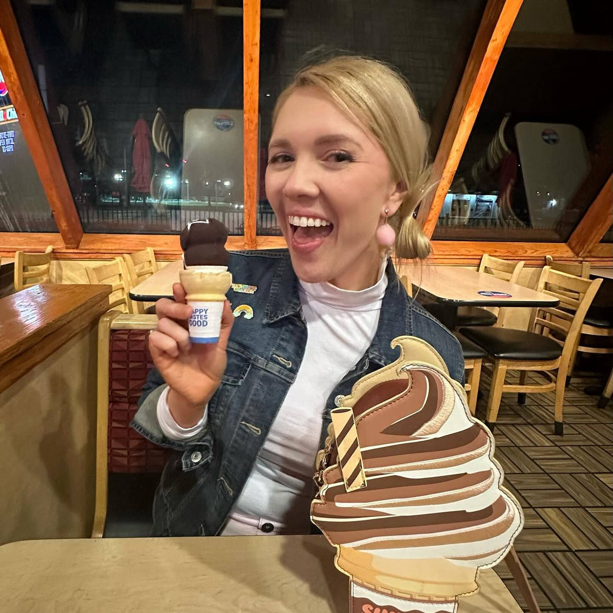 Woman holding a ice cream cone with a large ice cream cone cutout in a restaurant setting