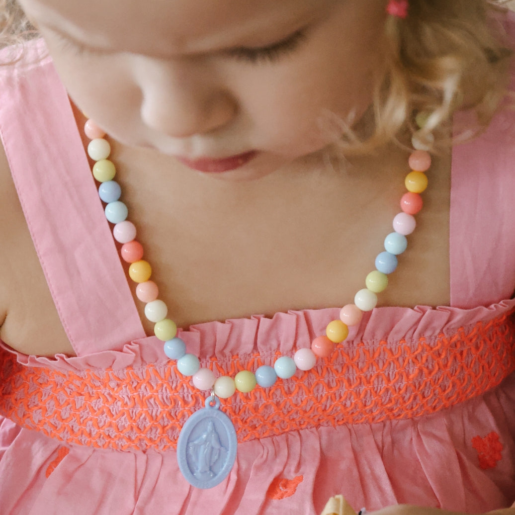Child wearing a colorful beaded necklace with a pink dress