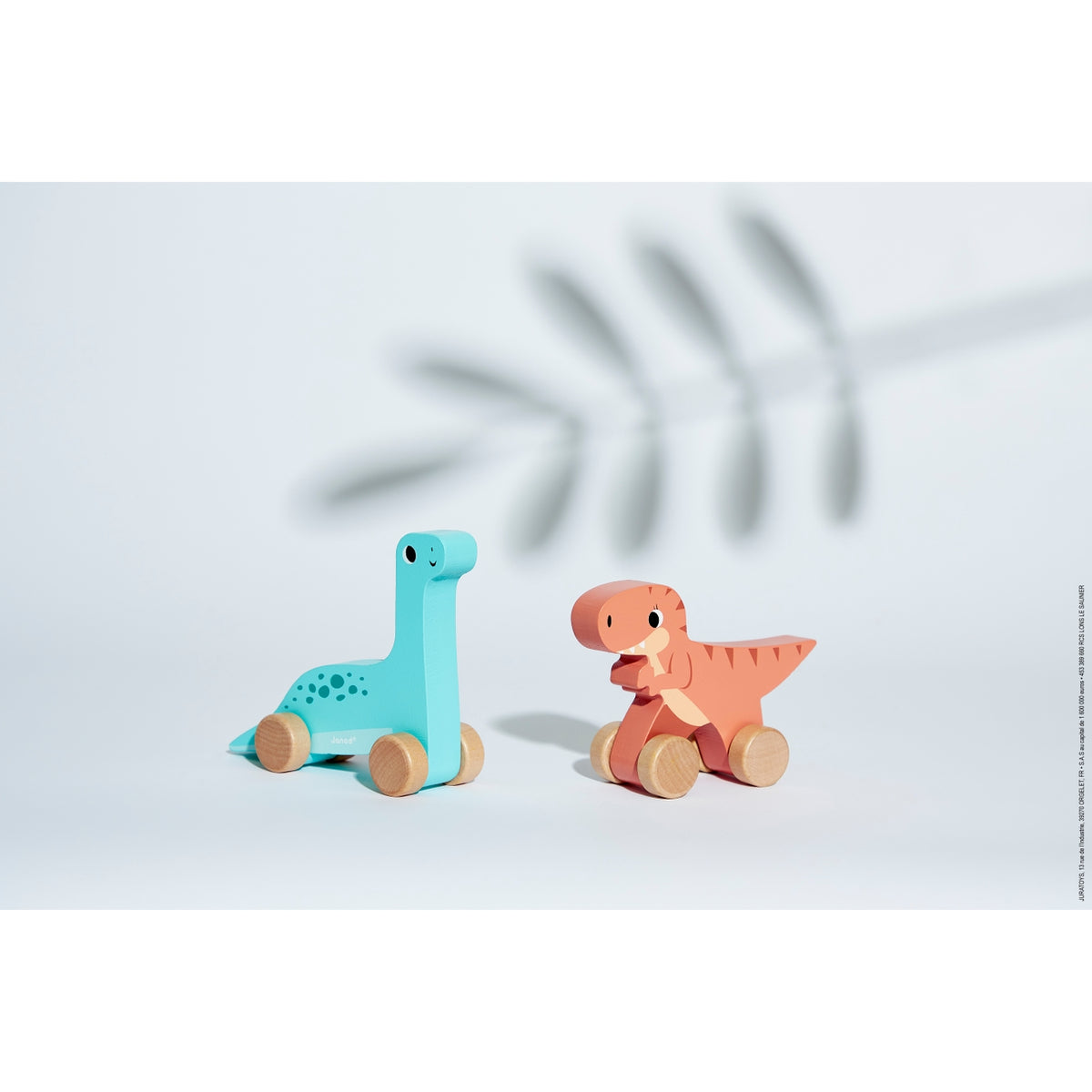 Two wooden dinosaur toys on a light background with a leaf shadow.