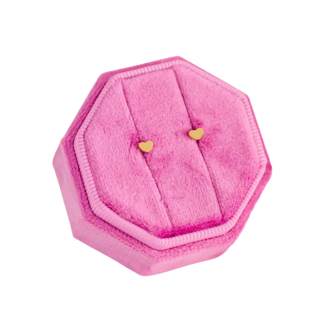 Pink hexagonal jewelry box with heart-shaped earrings on a white background