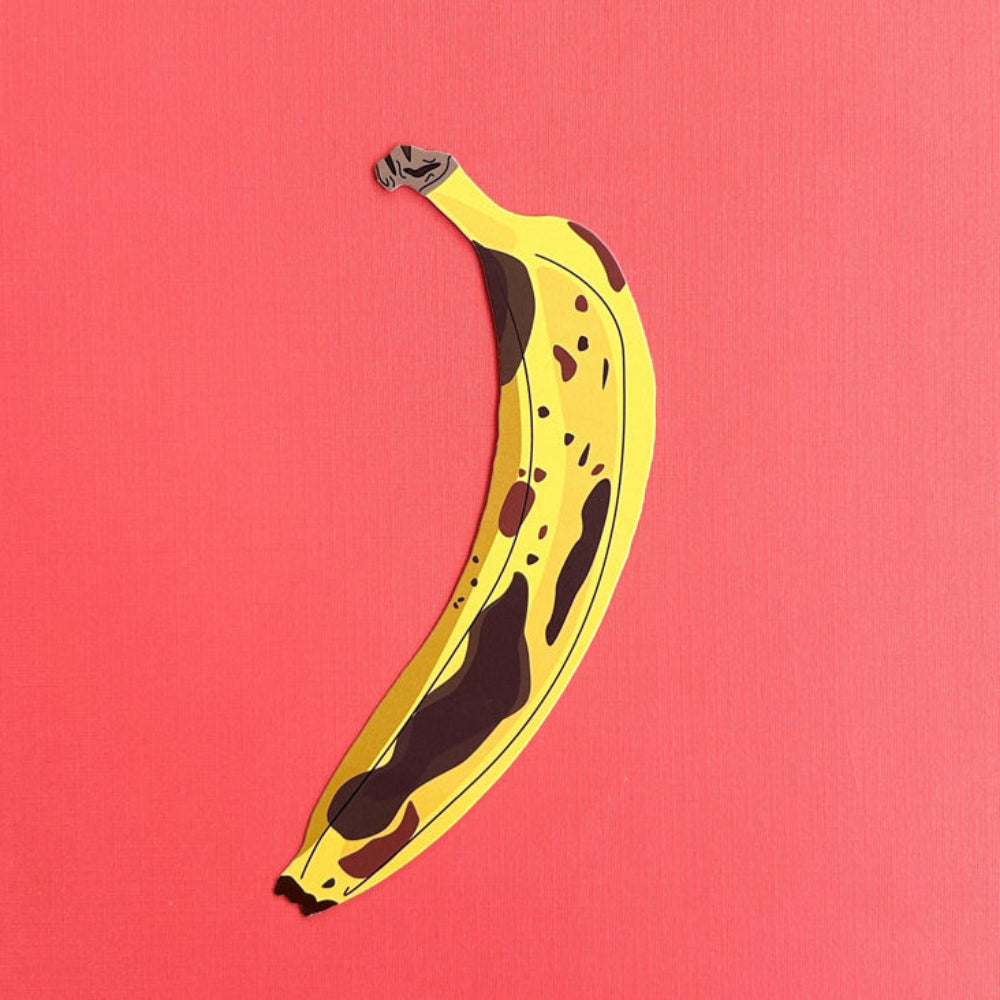 Yellow banana with brown spots on a pink background