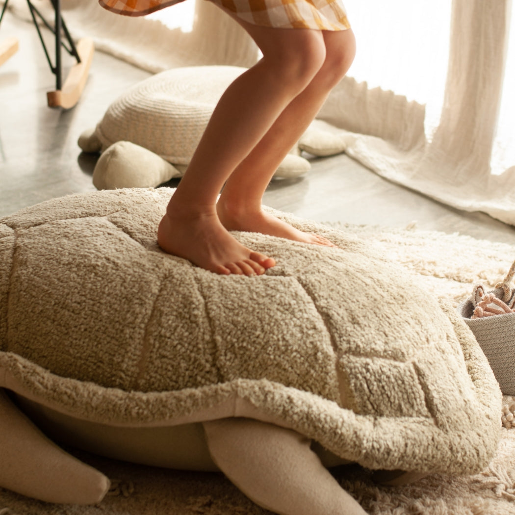 Child standing on a textured pillow in a cozy room with soft lighting